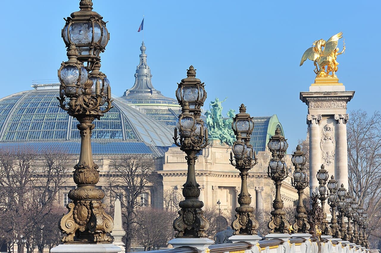 The ornate lamp posts of the Pont Alexandre III in Paris, with the Grand Palais behind